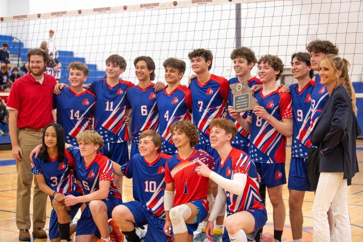 The volleyball team poses for a photo with the district champion plaque.