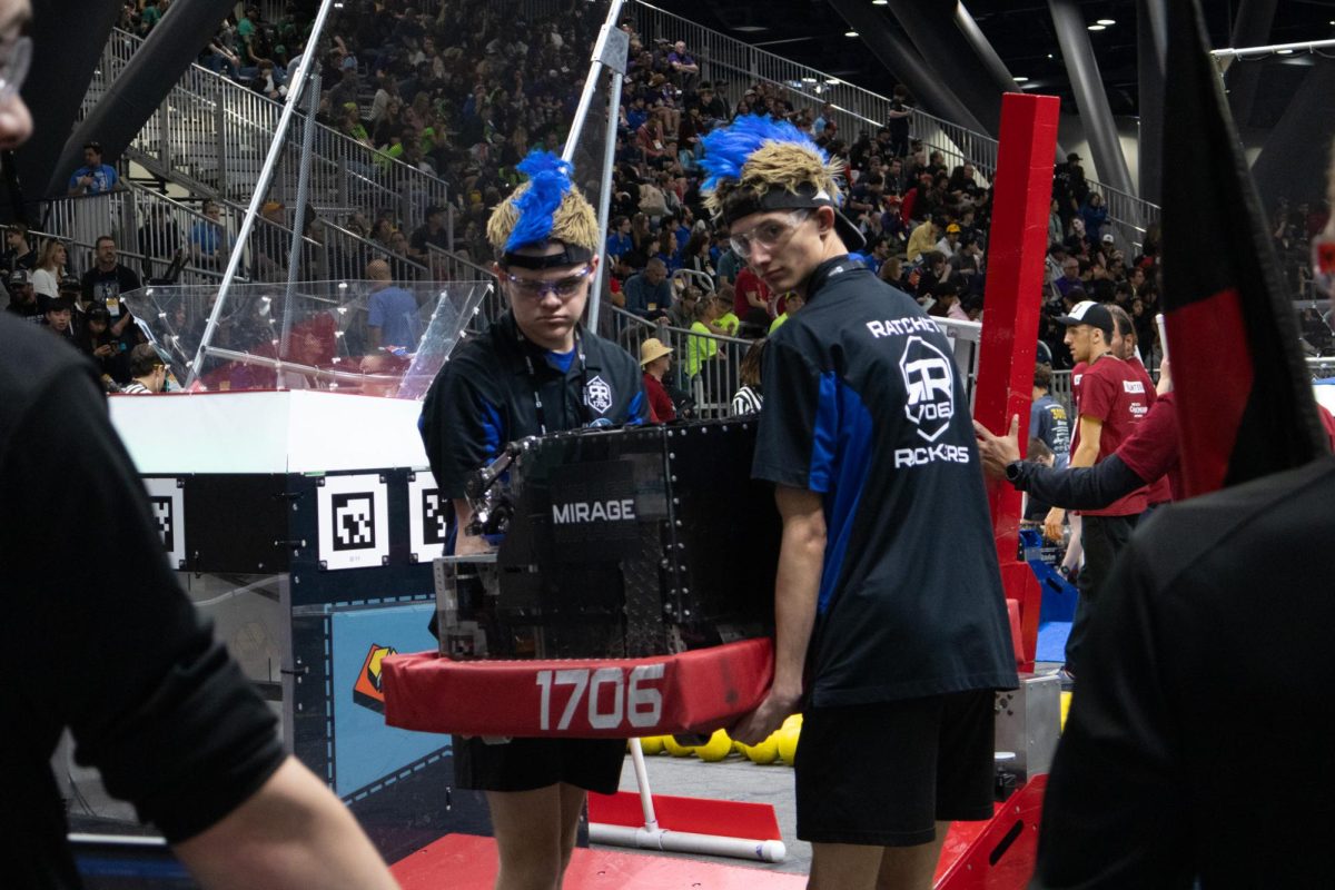 Driver for the robot, Brenden Buchanan (Liberty) and human player, Patrick Brown (Holt) carry the robot, Mirage, off the field.