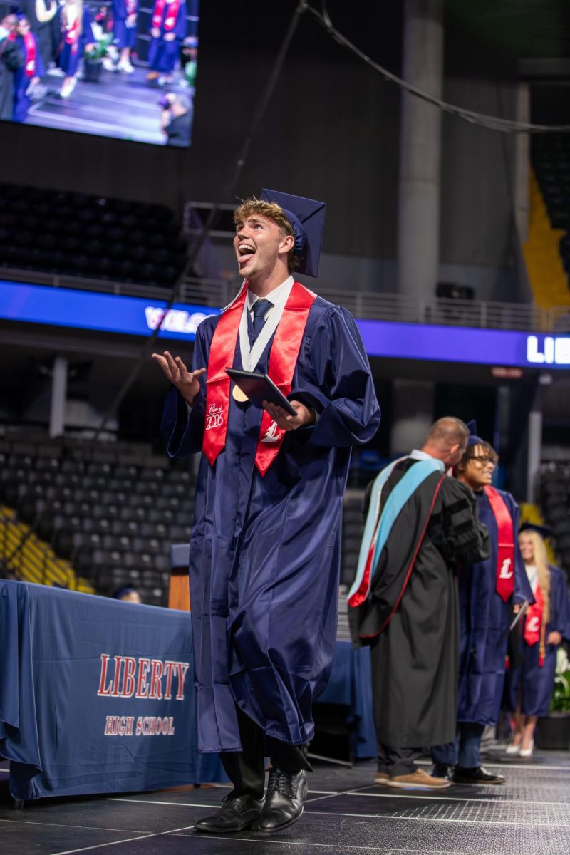 Austin Kelly does "six-seven" with his hands after receiving his diploma.