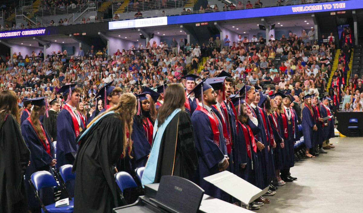 Class of 2026 students stand at their seats while waiting for the Commencement to start. 