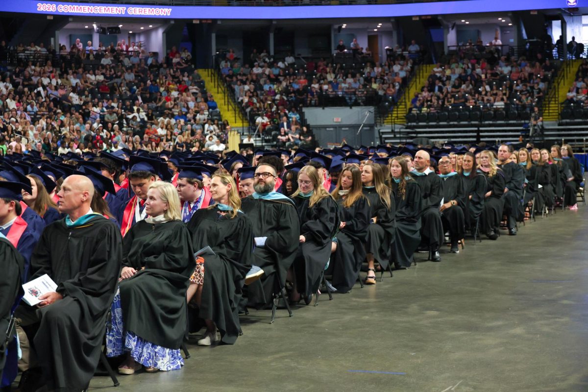 Liberty staff members sits at the end of each row of graduates.