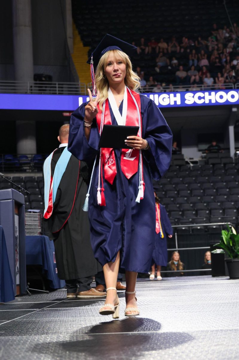 Ashlan Brantley sticks her tongue out and hold up a peace sign after receiving her diploma.